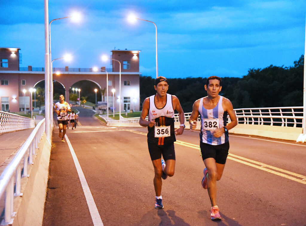 Cayendo. la tarde con fondo de los arcos de la Isla del Puerto, maratonistas cruzando el puente.